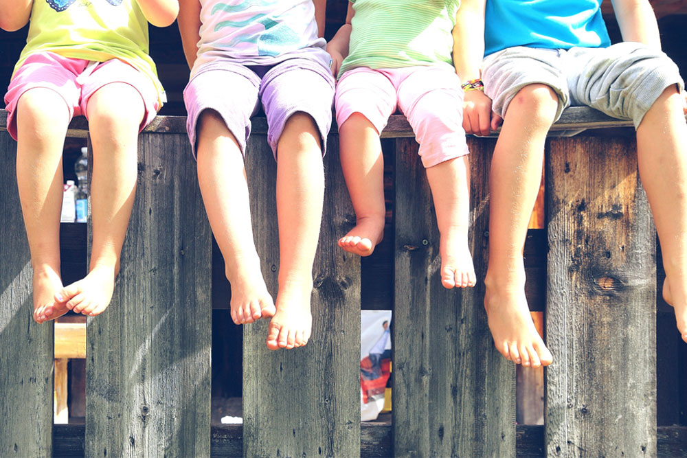 Kids hanging feet and legs over fence